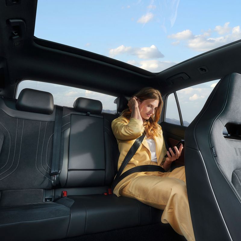Une femme assise à l'arrière d'un Volkswagen ID.5, vue par le toit ouvrant panoramique.
