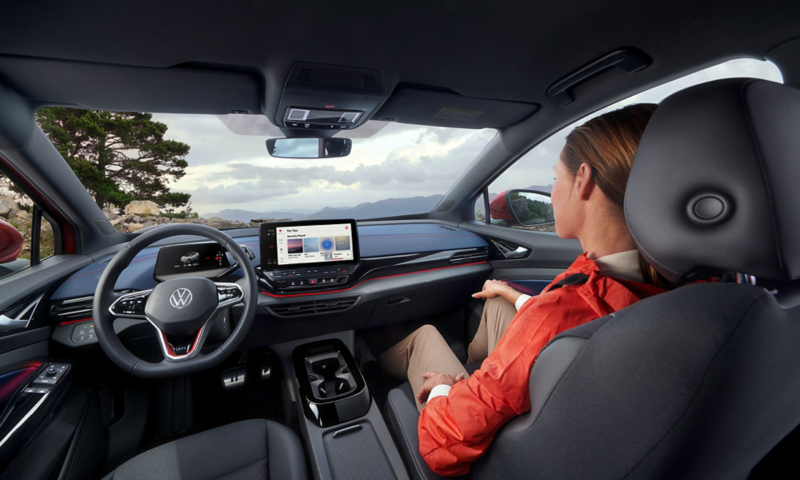 VW ID.5 GTX view from the inside. View of fittings, steering wheel, seats and pedals. A young woman is sitting in the passenger seat. 