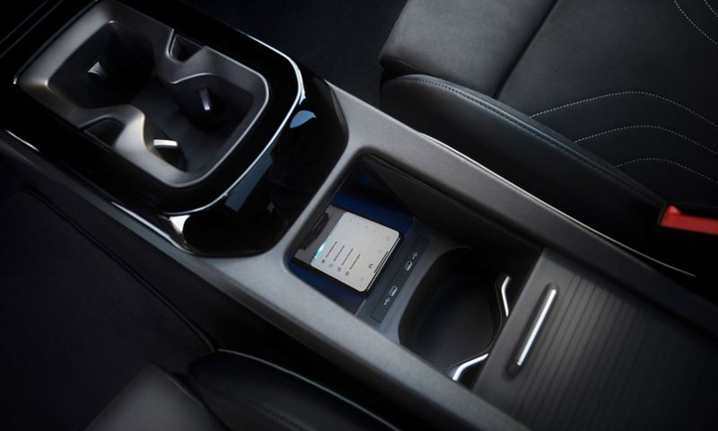 Vue de l'espace entre les sièges avant du Volkswagen ID.5. Un porte gobelet et un compartiment de rangement qui permet de recharger son smartphone.