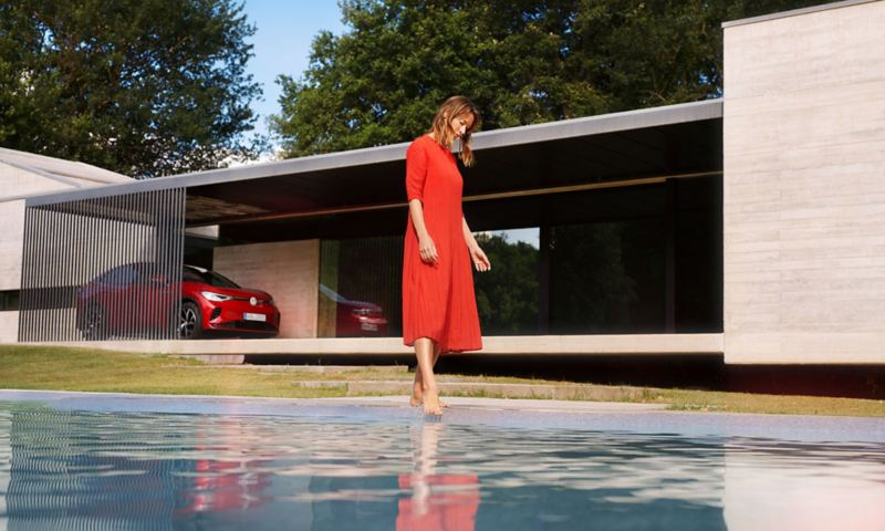 VW ID5 GTX SUV coupè parkert utenfor et hus, en kvinne står foran ved et basseng