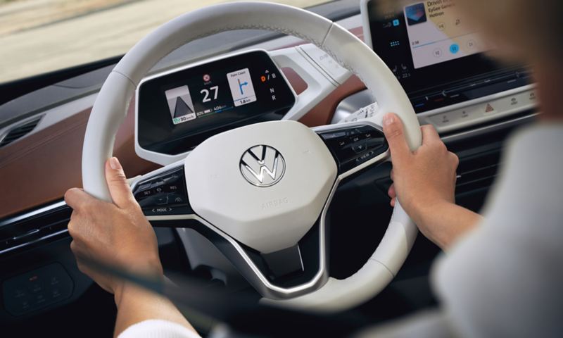 Detailed view of a white multifunction steering wheel in the VW ID.4 with view of speedometer. 