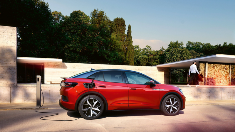 Ein roter VW ID.5 GTX lädt an einer Ladestation vor einem modernen Gebäude.