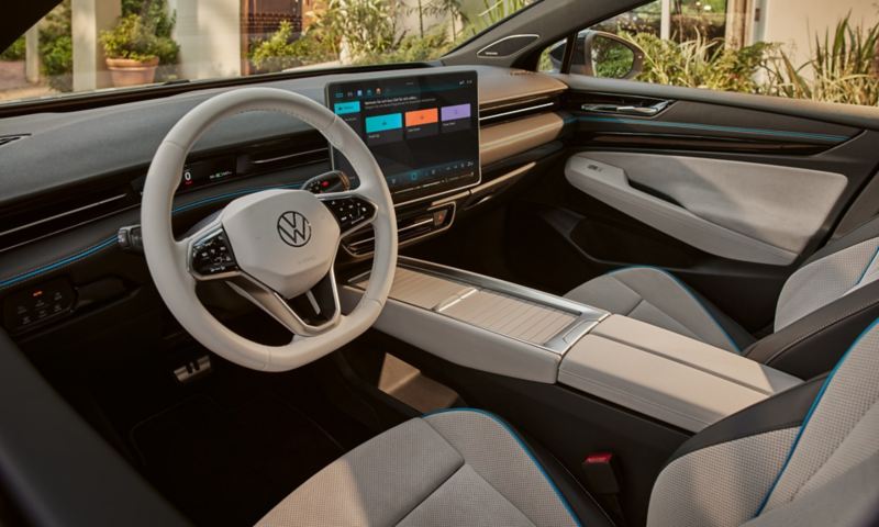 Zicht vanaf de achterbank van de VW ID.7 naar voren. Een vrouw zit op de bestuurdersstoel met een smartphone in de hand.