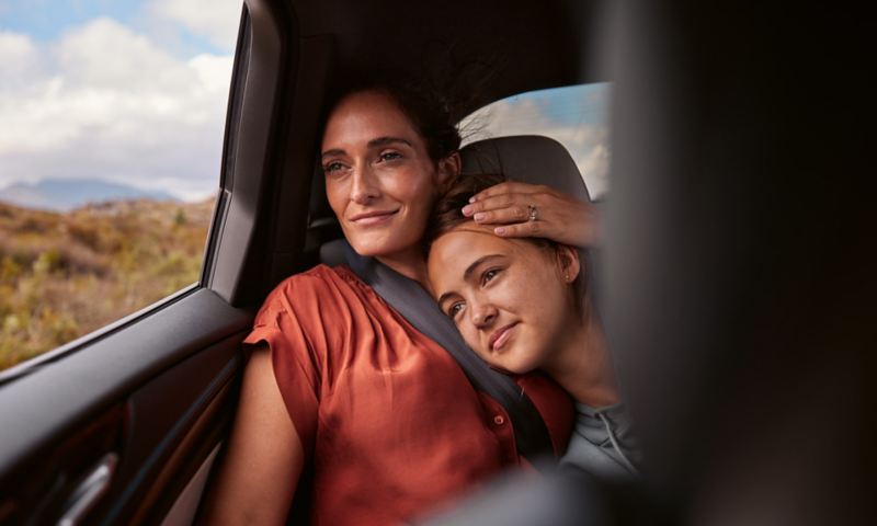 A woman and a teenager sit in the back seat of a VW ID.7 and look out the window together.