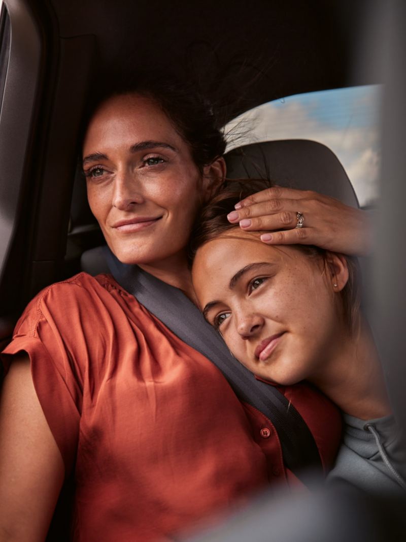 A woman and a teenager sit in the back seat of a VW ID.7 and look out the window together.