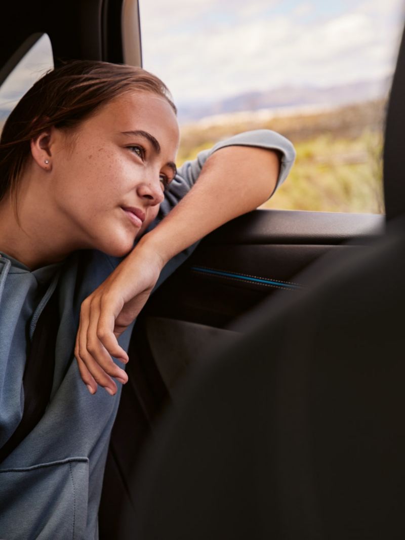 En ung kvinde på bagsædet i en VW ID.7, som kigger ud gennem ruden.