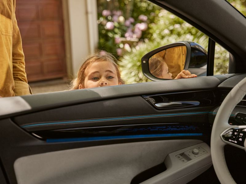 Une fillette regarde l'intérieur de la VW ID.7 par la fenêtre conducteur ouverte.