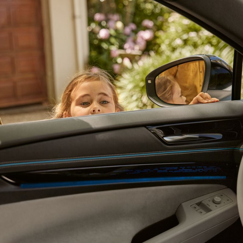 Une fillette regarde l'intérieur de la VW ID.7 par la fenêtre conducteur ouverte.