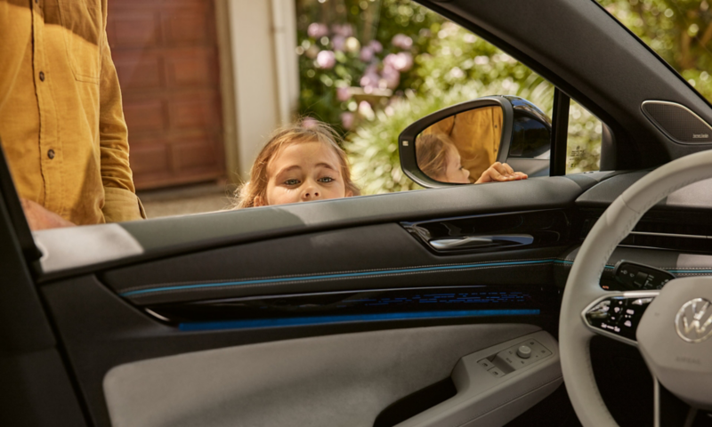 Une fillette regarde l'intérieur de la VW ID.7 par la fenêtre conducteur ouverte.