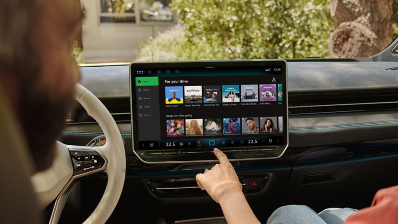 Cilvēki Volkswagen automašīnā skatās Spotify In-Car lietotni