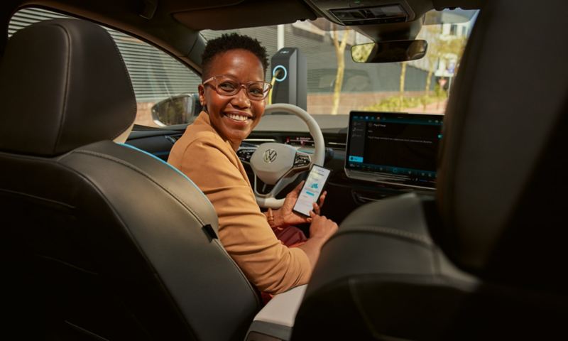 Blick vom Rücksitz des VW ID.7 nach vorne. Eine Frau sitzt auf dem Fahrersitz und hat ein Smartphone in der Hand.