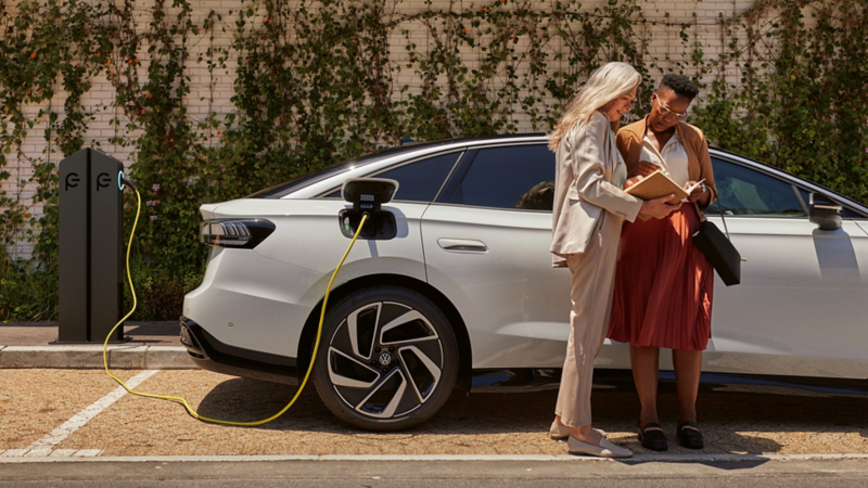 Zwei Personen stehen neben einem ladenden Volkswagen ID. an einer öffentlichen Ladesäule.