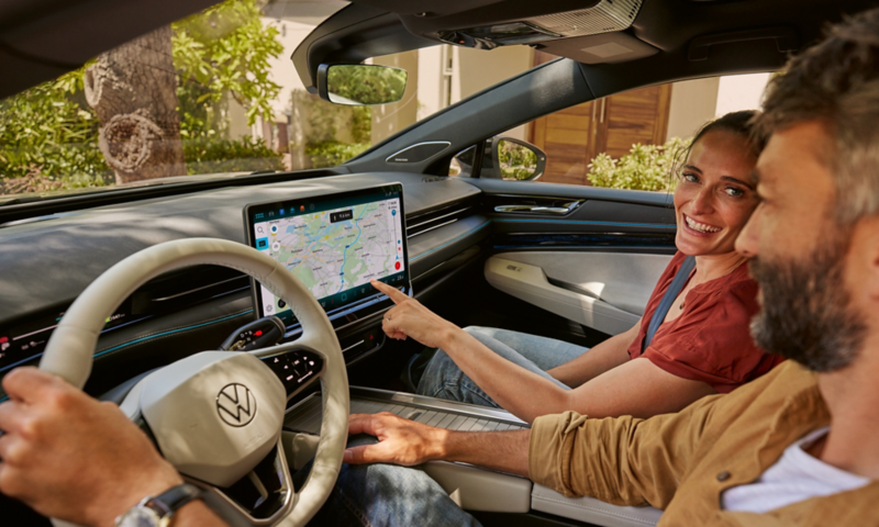 Une femme et un homme, à l'intérieur d'une Volkswagen ID. avec la carte de navigation affichée sur l'écran d'infodivertissement.