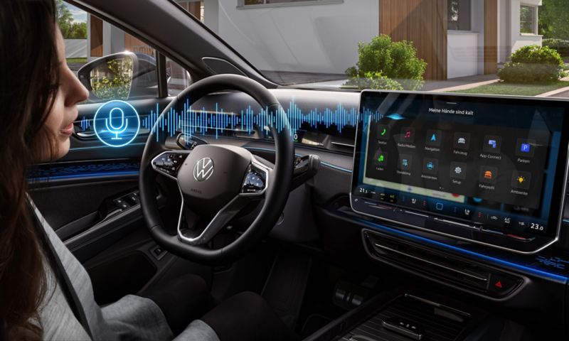 A woman sits in the driver's seat in the VW ID.7 and talks to the language assistant.