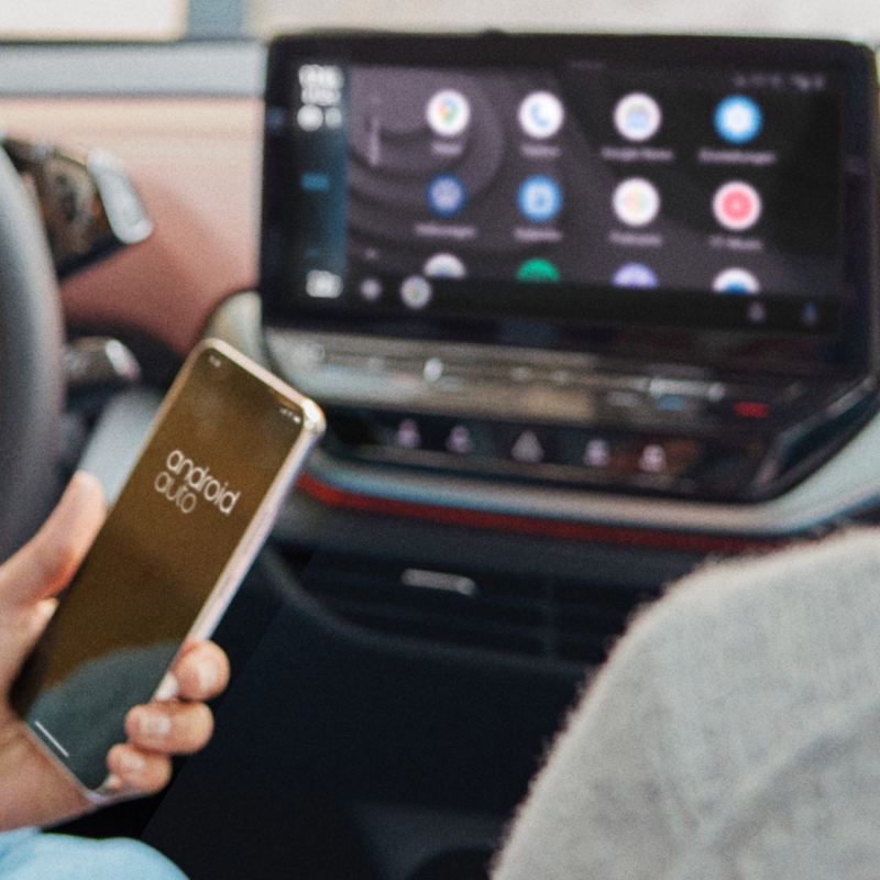 A woman sitting in a Volkswagen looking at her phone