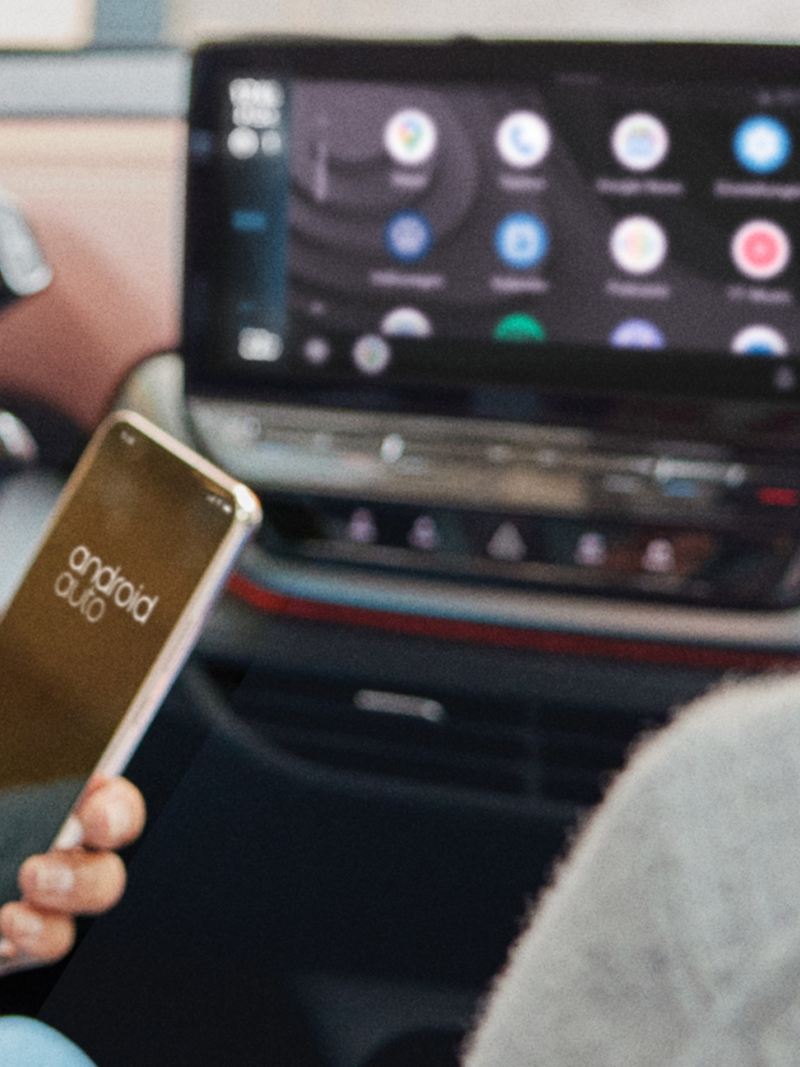 A woman sitting in a Volkswagen looking at her phone