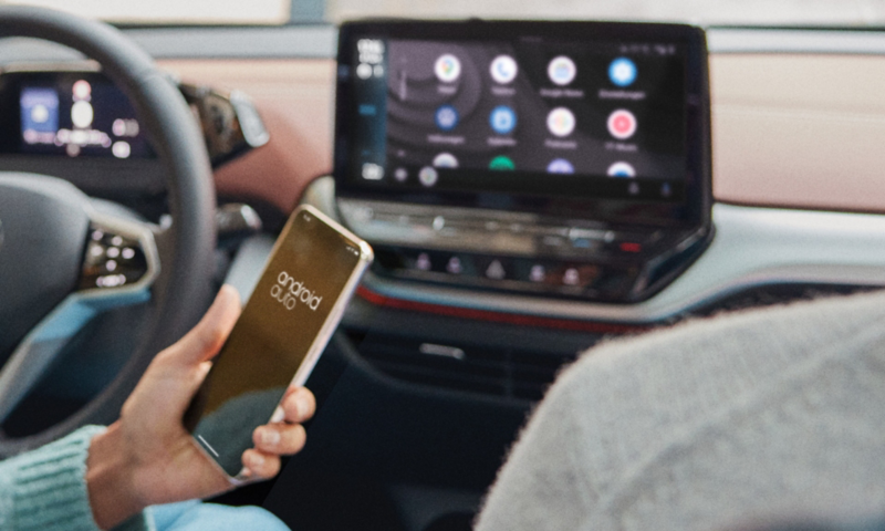 Une personne utilise son smartphone devant la console centrale d'une VW ID.