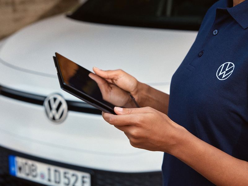 a hand of a Volkswagen representative holding a tablet in front of a white ID.5