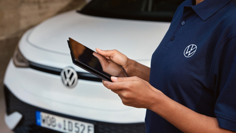 a hand of a Volkswagen representative holding a tablet in front of a white ID.5