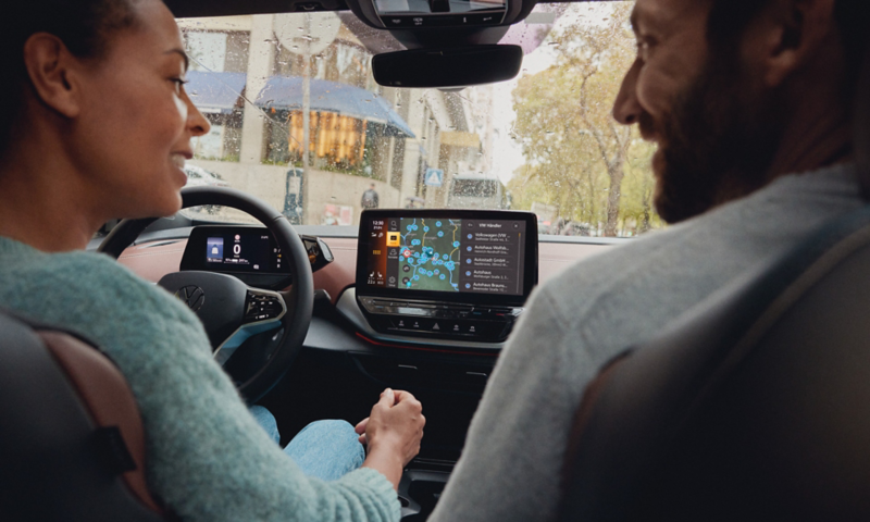 Une femme et un homme, à l'intérieur d'une Volkswagen ID. avec la carte de navigation affichée sur l'écran d'infodivertissement.