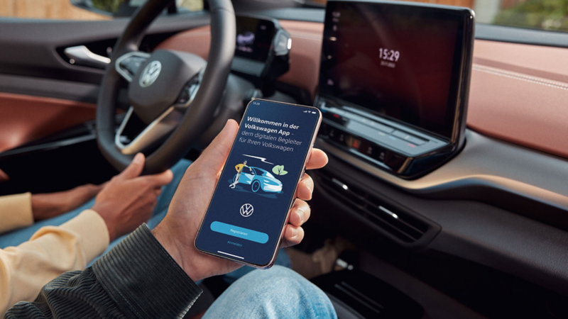 Zwei Personen sitzen vorne im ID.5 und nutzen die Volkswagen App auf dem Smartphone.