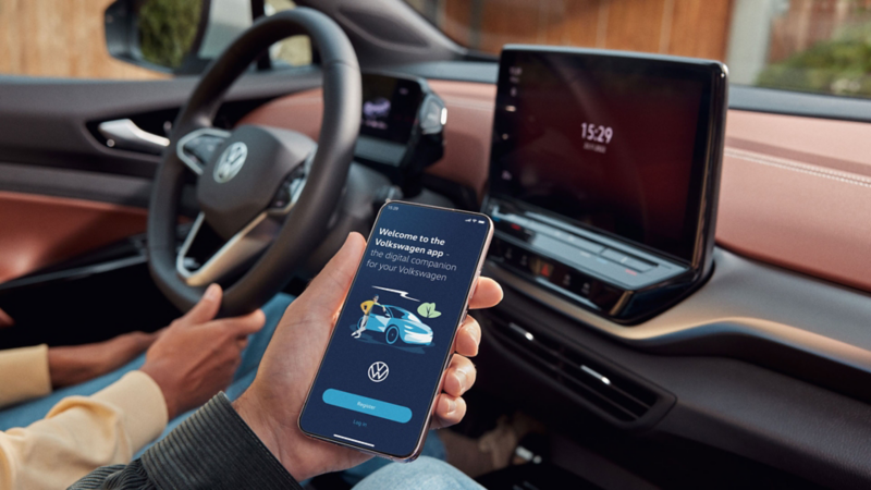To personer sidder foran i en ID.5 og bruger Volkswagen appen på en smartphone.