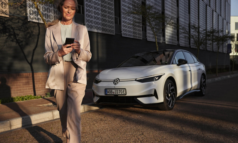 a woman looking at a smart phone. a white ID.7 is in the background