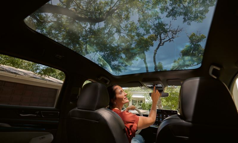 En kvinde betjener panoramaglastaget med Smart Glas i en VW ID.7.