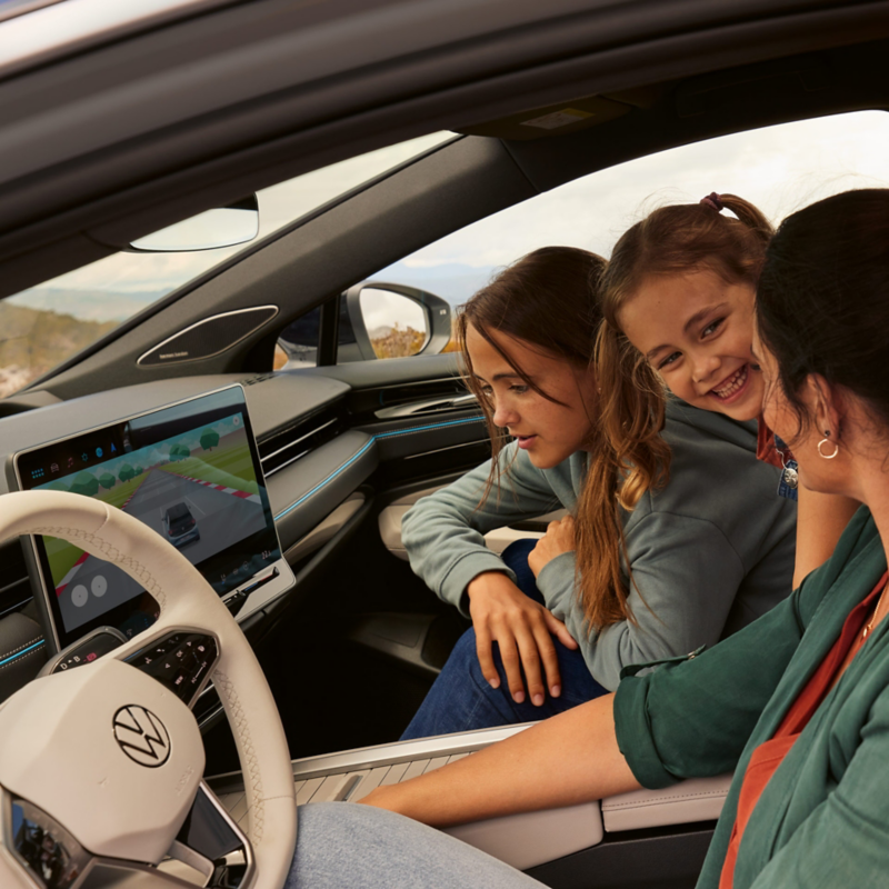 Une famille se trouve dans la VW ID.7, une des filles regarde le système d'infodivertissement où un jeu est en cours d'utilisation.