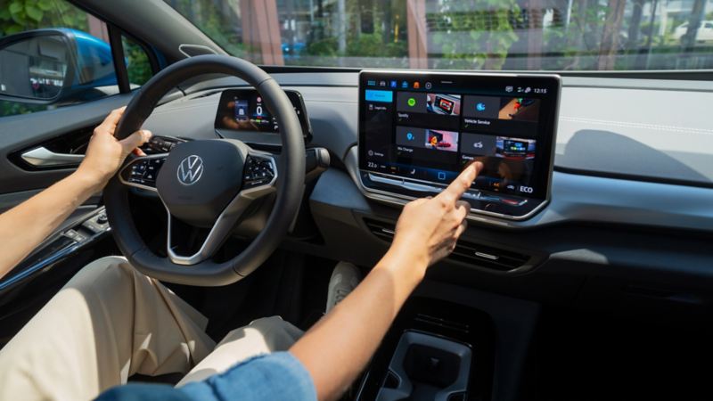Person på førersædet i en parkeret VW ID.4 betjener infotainmentsystemet. 
