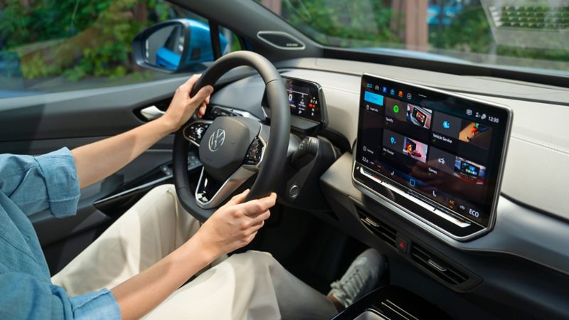 Lenkrad und Infotainment-System im VW ID.4, eine Frau sitzt auf dem Fahrersitz.