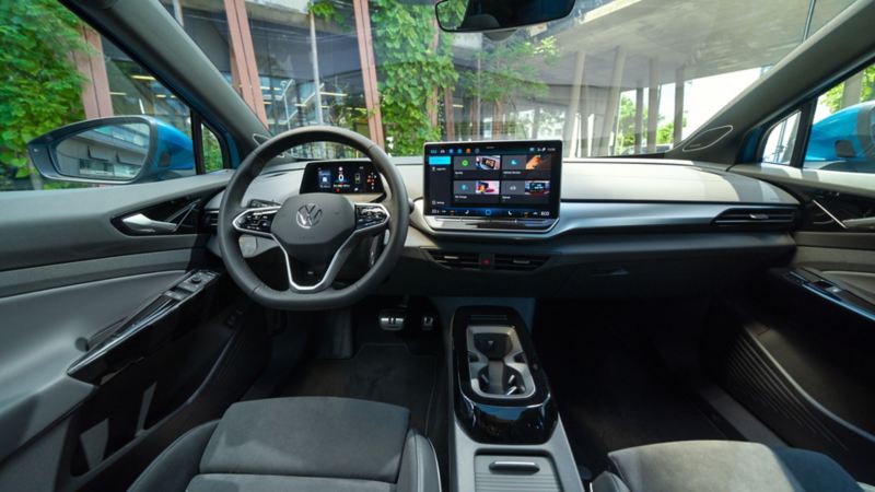 Innenansicht des Cockpit im VW ID.4 vom Fahrersitz aus. Zu sehen sind Mittelkonsole, Multifunktionslenkrad und grosses Touch-Display.