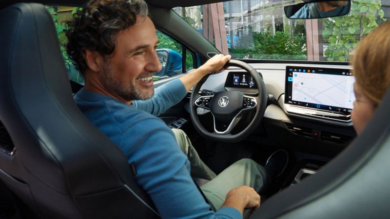 Un uomo sorridente alla guida di una Volkswagen ID.4.
