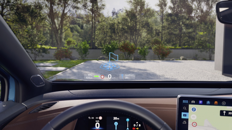 Detailansicht des AR-Head-up-Displays in der Windschutzsscheibe des VW ID.4, der in einer Einfahrt steht. Am unteren Bildrand sieht man durch das Lenkrad das digitale Cockpit.