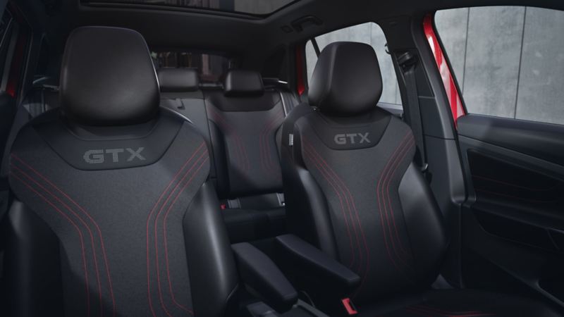 Kabinen i VW ID.4 GTX set fra midterkonsollen. Man kan se forsæderne med GTX-logo og røde detaljer samt en del af bagsædet.