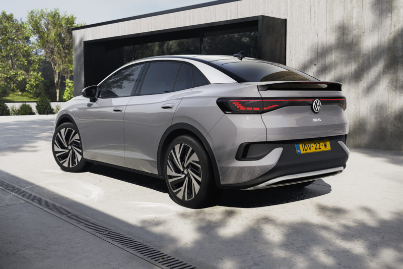 Schuin achteraanzicht van een grijze Volkswagen ID.5 die geparkeerd staat op een oprit naast een huis