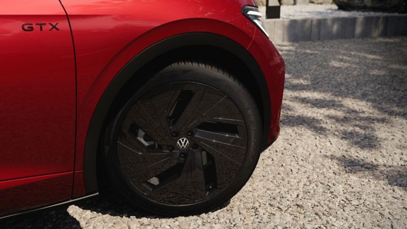 Detailansicht der schwarzen 21-Zoll-Leichtmetallfelgen Narvik auf dem rechten Vorderrad des roten VW ID.5 GTX.