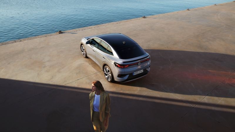 Heckansicht eines VW ID.5 an einem Hafenkai, Blick von schräg oben, im Vordergrund steht eine Frau
