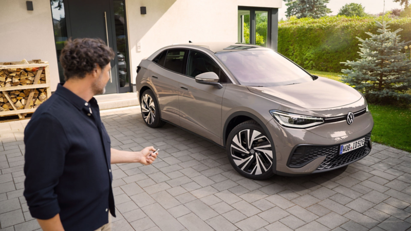 Ein Mann blickt auf einen grauen VW ID.5, der vor einem Einfamilienhaus steht.