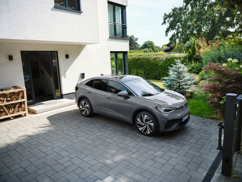 En grå VW ID.5 holder parkeret i en indkørsel foran et moderne hus.
