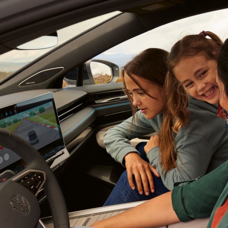 "A family is sitting in the VW ID.7, one of the girls is looking at the display of the infotainment system where a game is playing. "