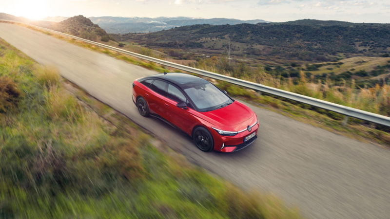 Czerwony Volkswagen ID.7 GTX jedzie przez drogę.