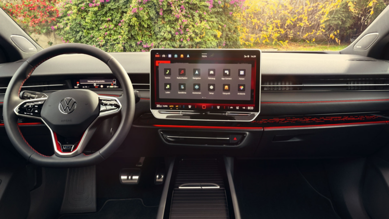 Cockpit eines VW ID.7 GTX mit Multifunktionslenkrad und Infotainmentsystem mit roten Akzenten.