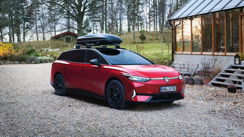 A red VW ID.7 Tourer GTX parked outside a lakeside house