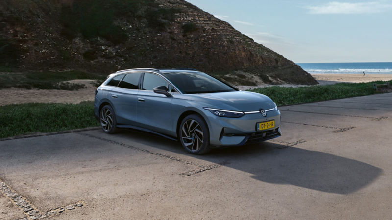 Zijaanzicht Volkswagen ID.7 Tourer bij het strand tussen in bergachtig gebied
