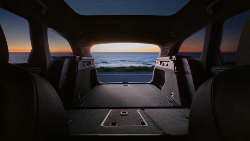 the inside of an ID.7 Tourer with the boot open looking out onto the ocean over an orange sunset