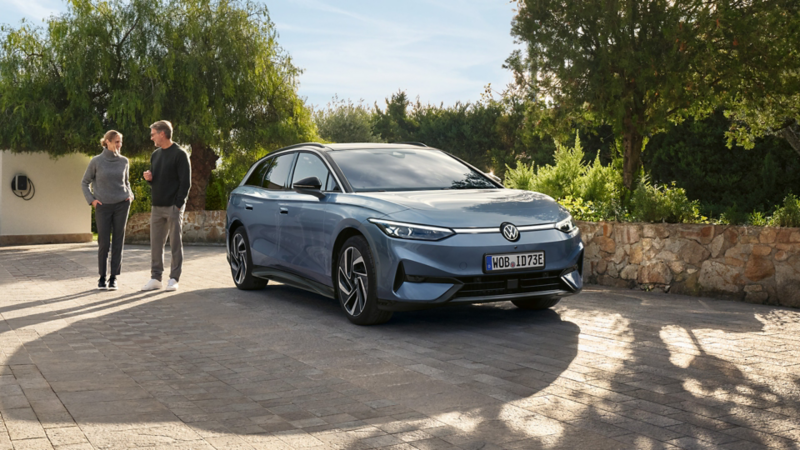 Un uomo e una donna che si allontanano da una Volkswagen ID.7 Tourer.