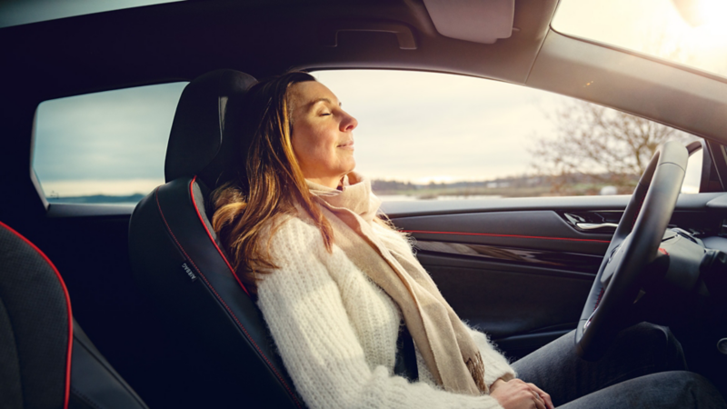 Eine Frau sitzt entspannt im VW ID.7 GTX Tourer, sichtbar sind Lenkrad und Infotainment-Display.