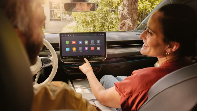 Ein Mann und eine Frau sitzen  im VW ID.7. Die Frau bedient das Infotainmentsystem.