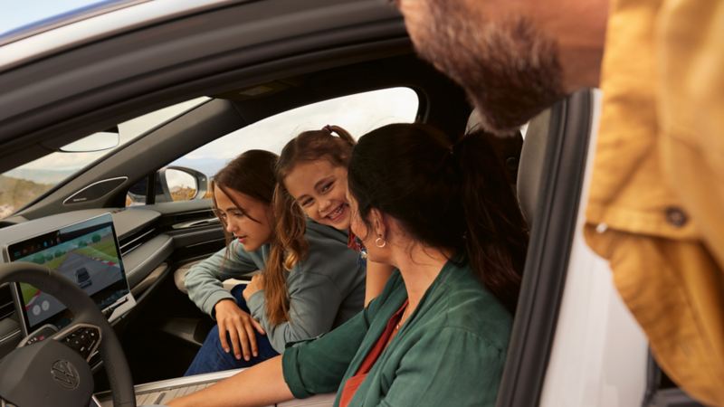 Eine Familie sitzt im VW ID.7, eines der Mädchen schaut auf das Display.